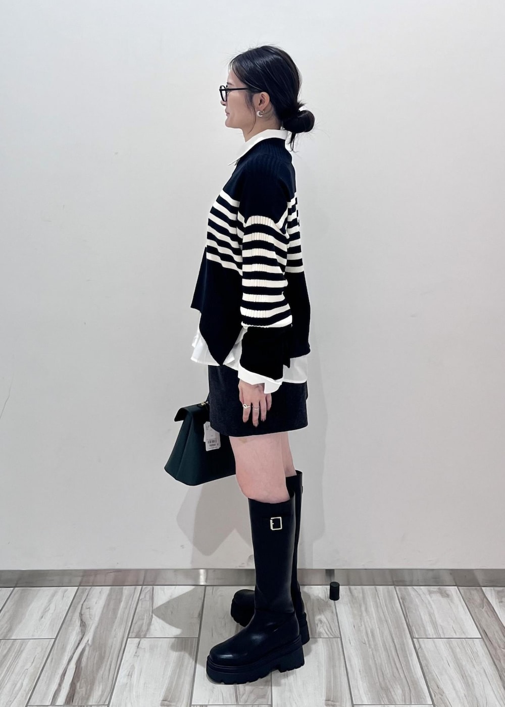 ブラック系のブーツ、ホワイト系のシャツ/ブラウス、ブラック系のニット/セーターを着用したレディースの秋コーディネートの4枚目の写真