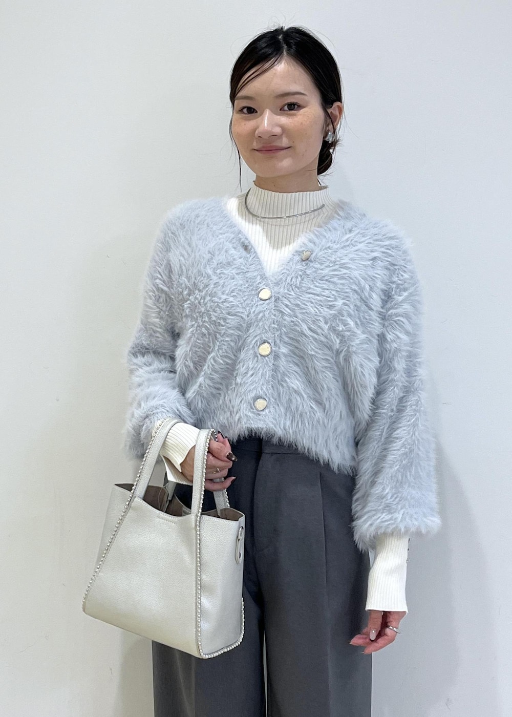 グレー系のスラックス、ホワイト系のパンプス、ブルー系のカーディガン/ボレロを着用したレディースの秋コーディネートの8枚目の写真