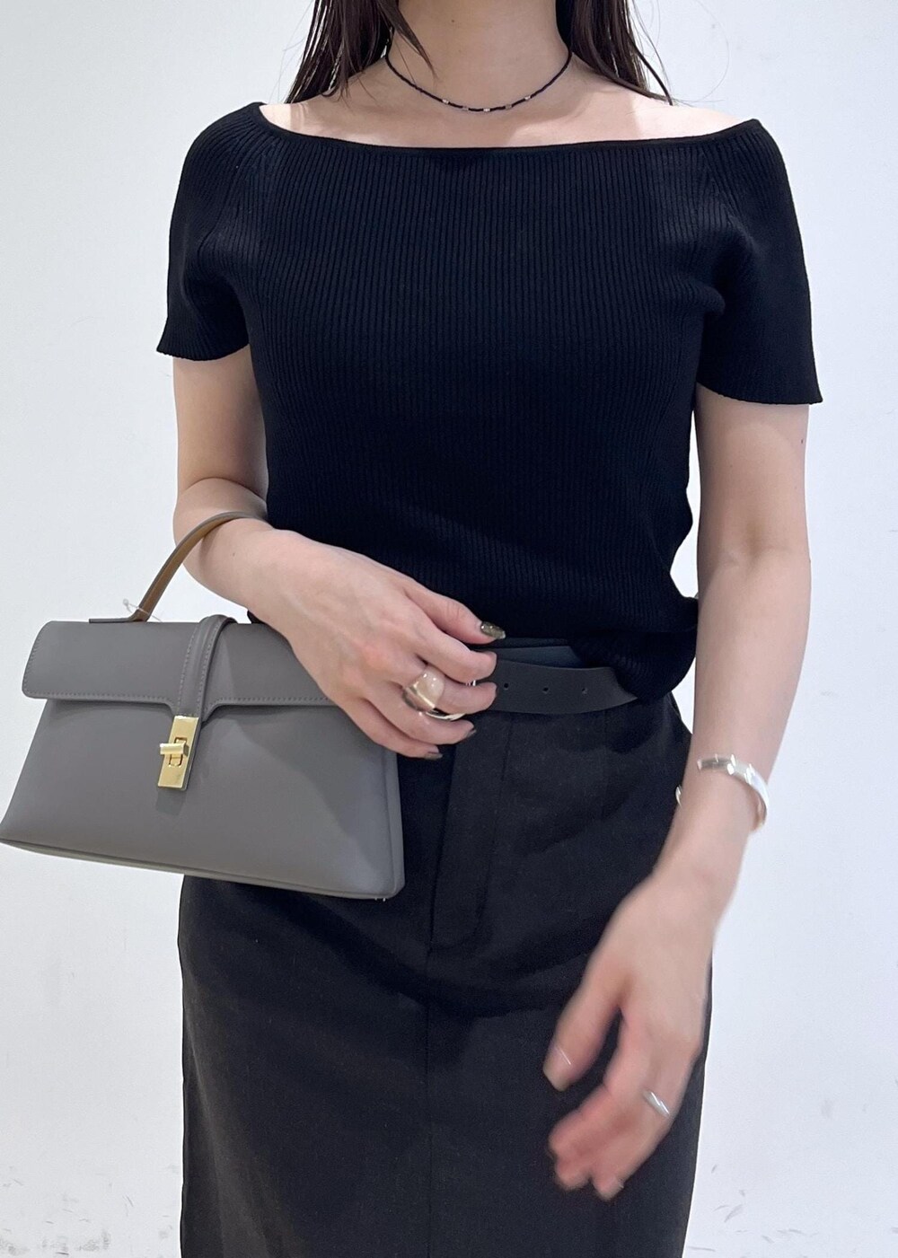 グレー系のショルダーバッグ、グレー系のスカート、ブラック系のニット/セーターを着用したレディースの夏コーディネートの7枚目の写真