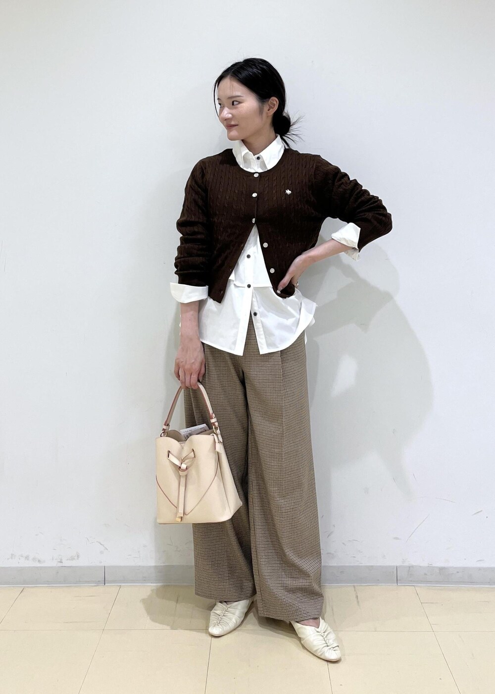 ベージュ系のショルダーバッグ、ベージュ系のスラックス、ホワイト系のシャツ/ブラウスを着用したレディースの秋コーディネートの5枚目の写真
