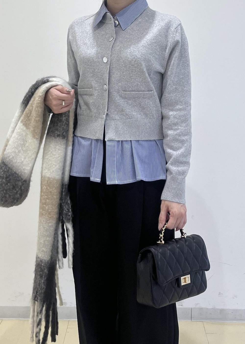 ホワイト系のパンプス、グレー系のカーディガン/ボレロ、ブラック系のスラックスを着用したレディースの冬コーディネートの3枚目の写真