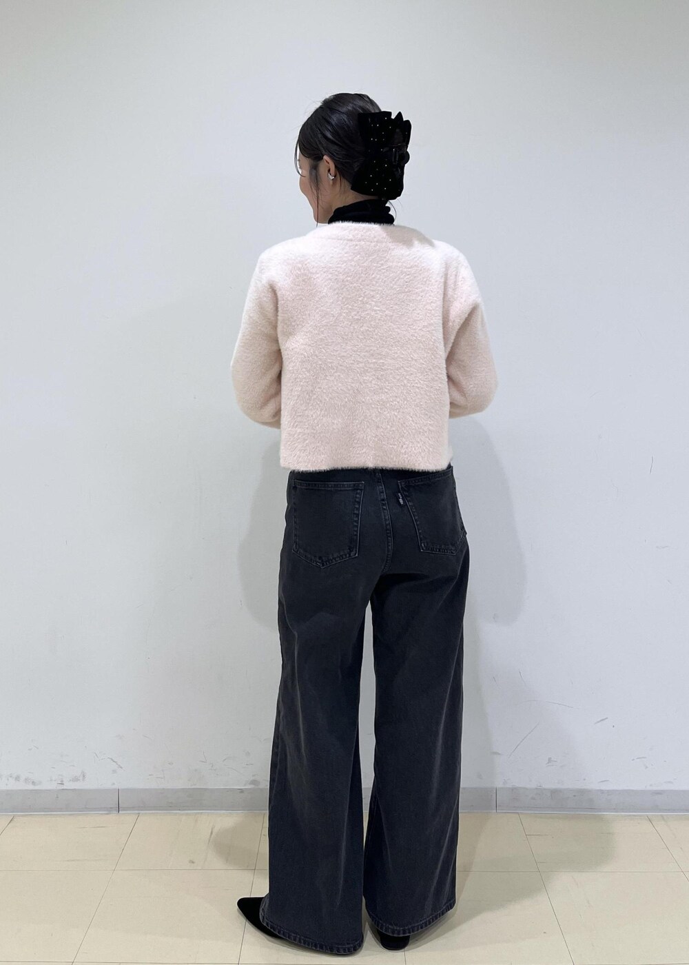 ブラック系のショルダーバッグ、グレー系のデニムパンツ、ピンク系のカーディガン/ボレロを着用したレディースの秋コーディネートの3枚目の写真