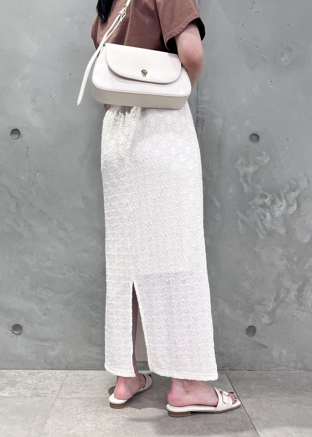 ホワイト系のショルダーバッグ、ホワイト系のサンダル、ブラウン系のTシャツ/カットソーを着用したレディースの夏コーディネートの3枚目の写真