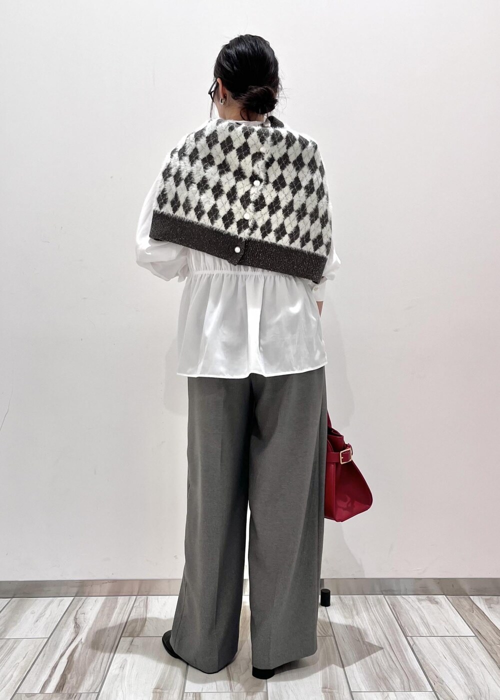 レッド系のトートバッグ、ブラック系のブーツ、ブラック系のカーディガン/ボレロを着用したレディースの秋コーディネートの4枚目の写真