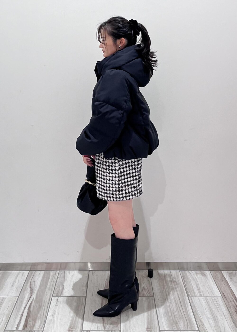 ブラック系のブーツ、ブラック系のスカート、ブラック系のダウンジャケット/コートを着用したレディースの冬コーディネートの2枚目の写真