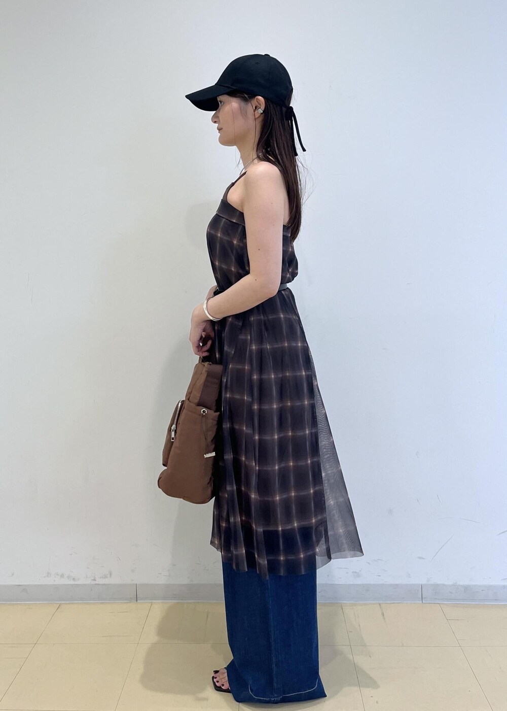 ブルー系のデニムパンツ、ブラウン系のスカート、ブラウン系のキャミソールを着用したレディースの夏コーディネートの3枚目の写真