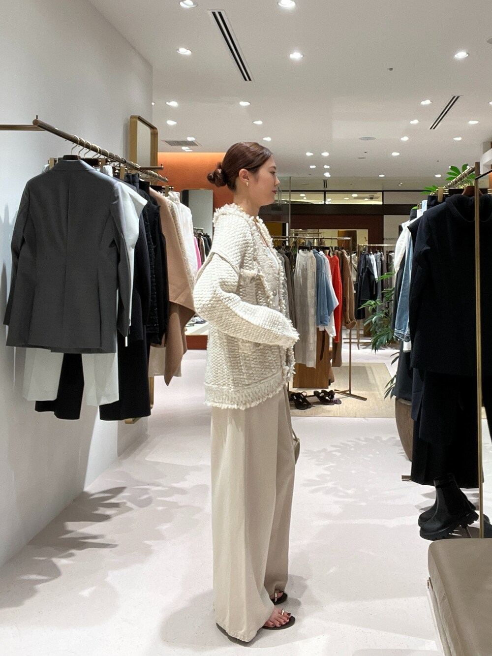 ベージュ系のデニムパンツ、ベージュ系のハンドバッグ、ゴールド系のサンダルを着用したレディースの秋コーディネートの3枚目の写真