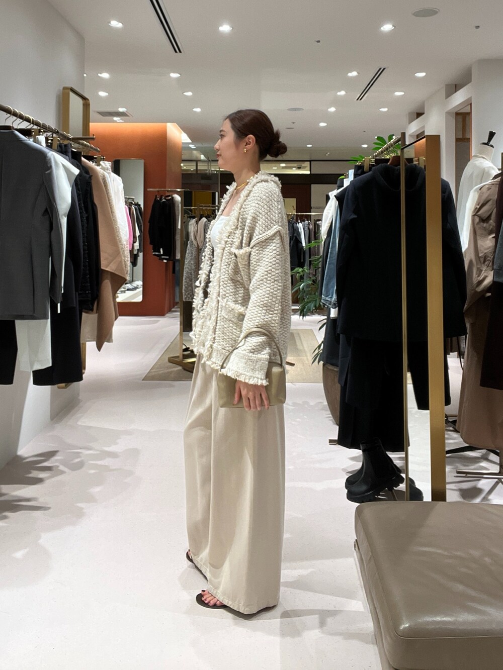 ベージュ系のデニムパンツ、ベージュ系のハンドバッグ、ゴールド系のサンダルを着用したレディースの秋コーディネートの5枚目の写真