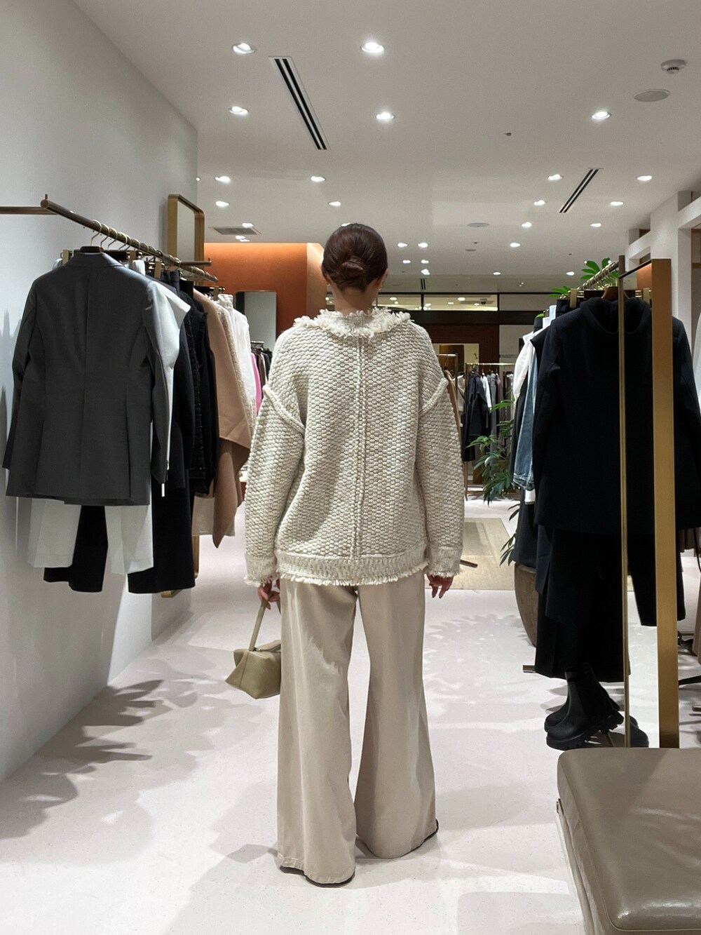 ベージュ系のデニムパンツ、ベージュ系のハンドバッグ、ゴールド系のサンダルを着用したレディースの秋コーディネートの4枚目の写真