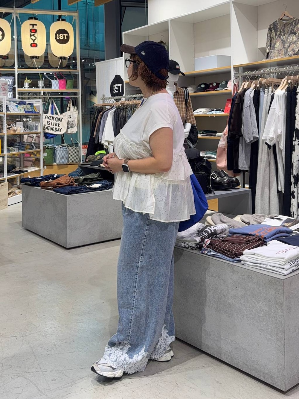 ベージュ系のTシャツ/カットソー、ブルー系のデニムパンツ、ブルー系のキャップを着用したレディースの秋コーディネートの4枚目の写真