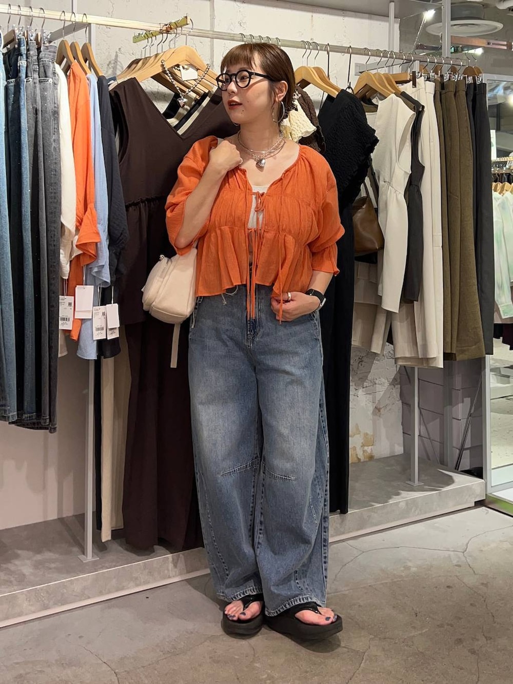 オレンジ系のシャツ/ブラウス、ブルー系のデニムパンツ、ゴールド系のタンクトップを着用したレディースの夏コーディネートの6枚目の写真