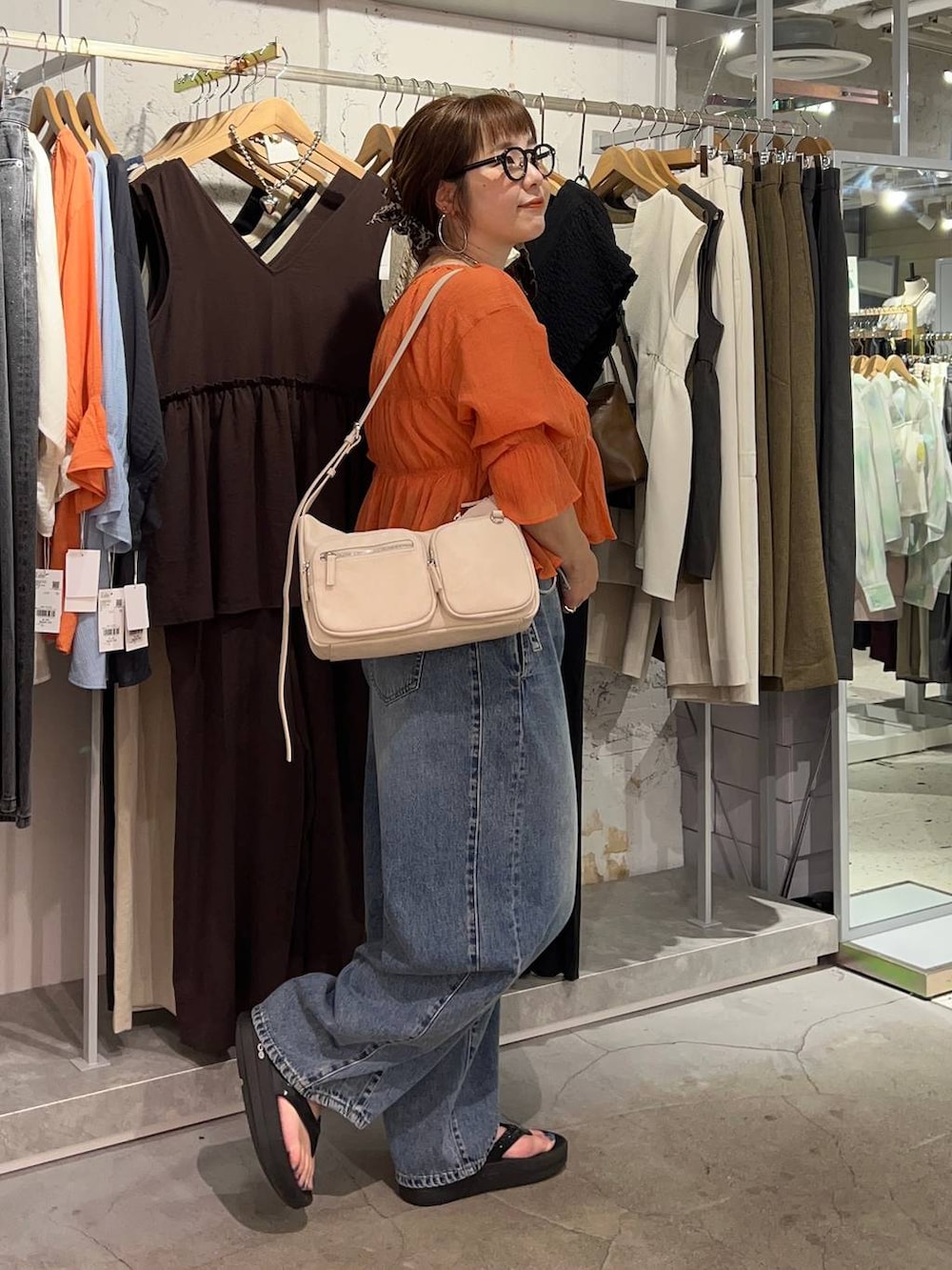 オレンジ系のシャツ/ブラウス、ブルー系のデニムパンツ、ゴールド系のタンクトップを着用したレディースの夏コーディネートの3枚目の写真