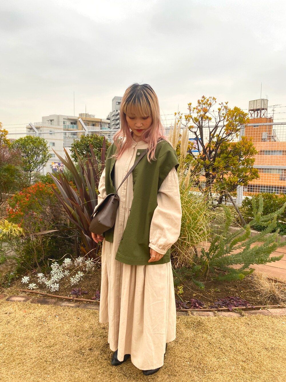 グリーン系のジャケット/アウター、ブラウン系のバッグ、ベージュ系のワンピース/ドレスを着用したレディースの冬コーディネートの2枚目の写真