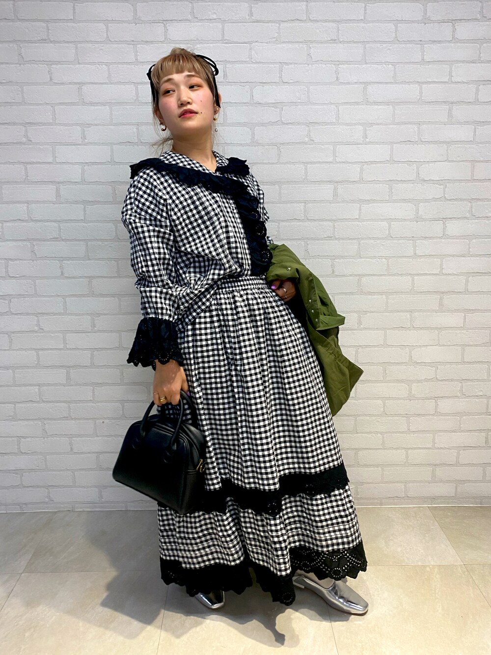 ブラック系のシャツ/ブラウス、グリーン系のジャケット/アウター、ブラック系のスカートを着用したレディースの春コーディネートの2枚目の写真