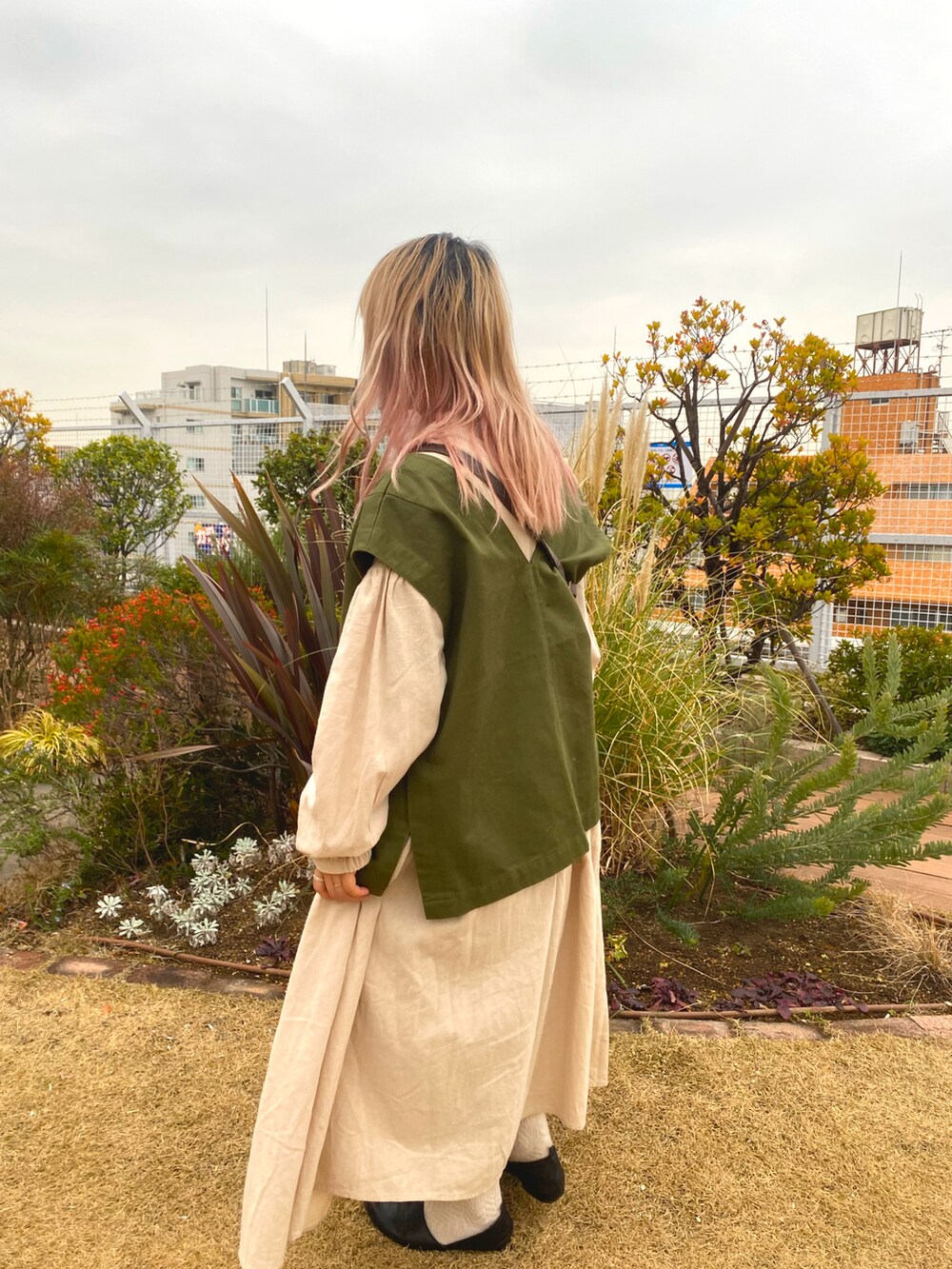 グリーン系のジャケット/アウター、ブラウン系のバッグ、ベージュ系のワンピース/ドレスを着用したレディースの冬コーディネートの4枚目の写真