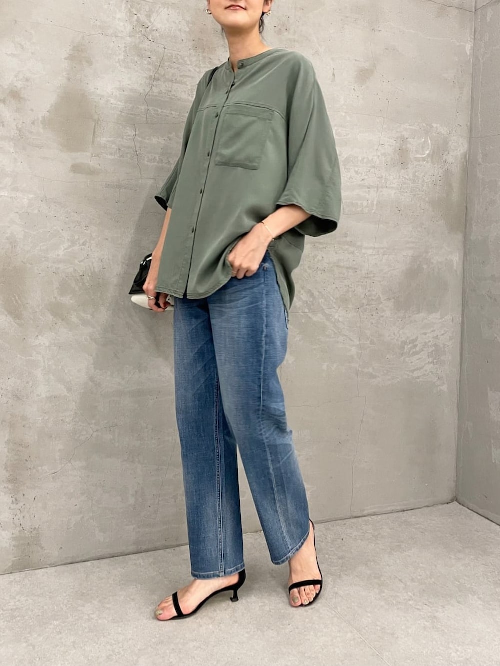 グリーン系のシャツ/ブラウス、ブラック系のショルダーバッグ、ブルー系のデニムパンツを着用したレディースの夏コーディネートの2枚目の写真