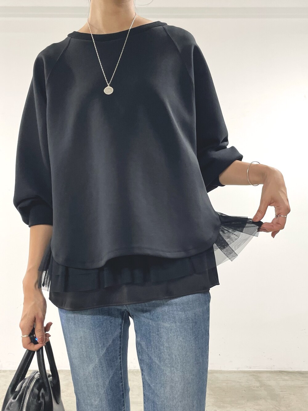 ブラック系のTシャツ/カットソー、ブラック系のキャミソール、ブルー系のデニムパンツを着用したレディースの秋コーディネートの4枚目の写真