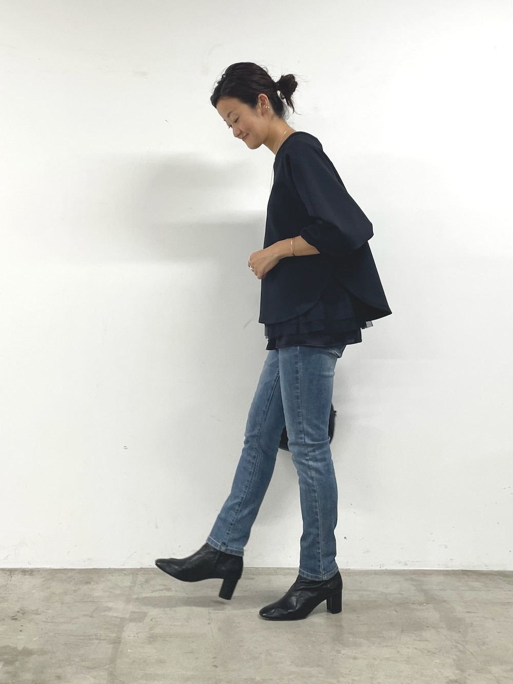 ブラック系のTシャツ/カットソー、ブラック系のキャミソール、ブルー系のデニムパンツを着用したレディースの秋コーディネートの2枚目の写真