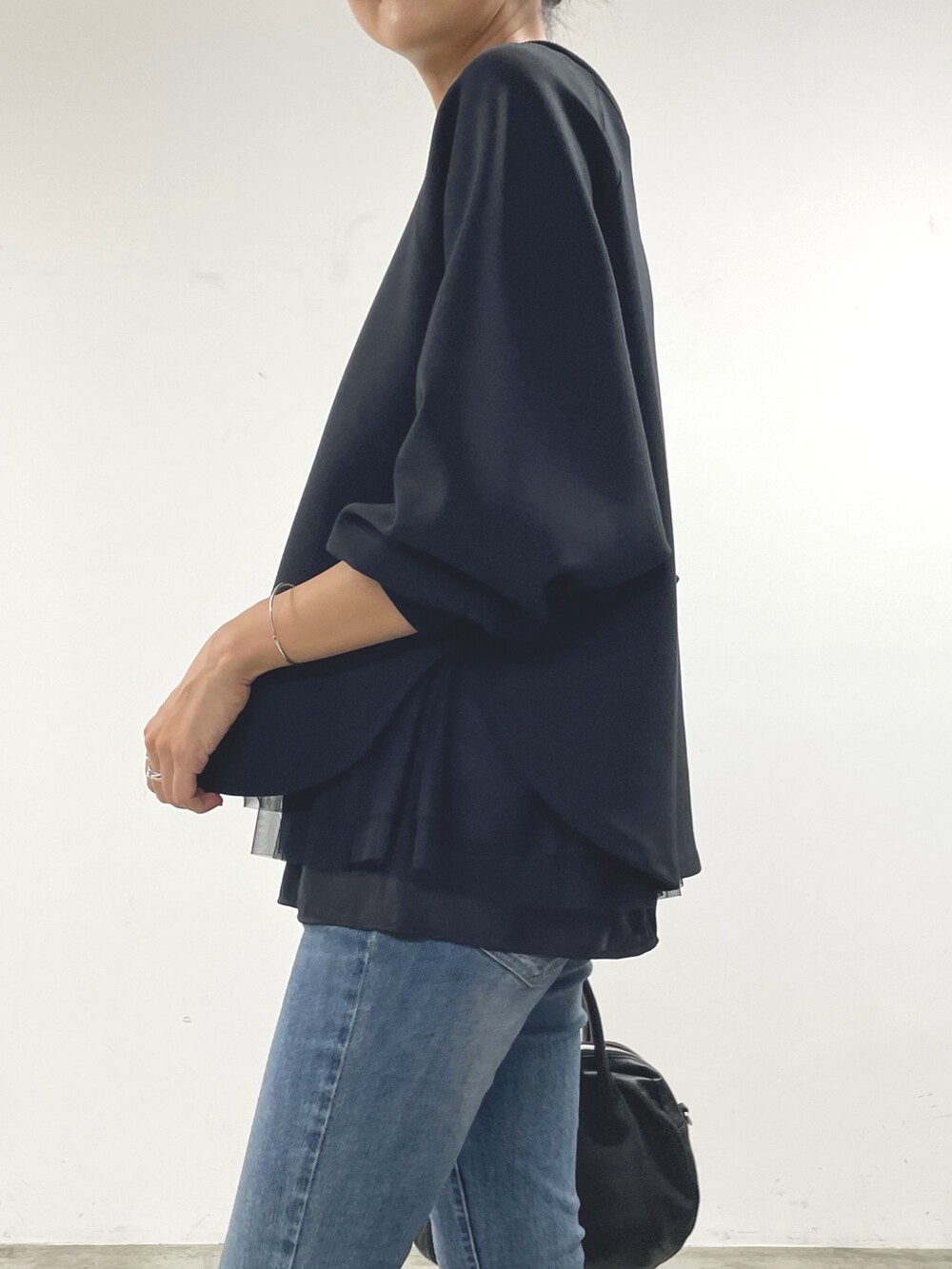 ブラック系のTシャツ/カットソー、ブラック系のキャミソール、ブルー系のデニムパンツを着用したレディースの秋コーディネートの5枚目の写真