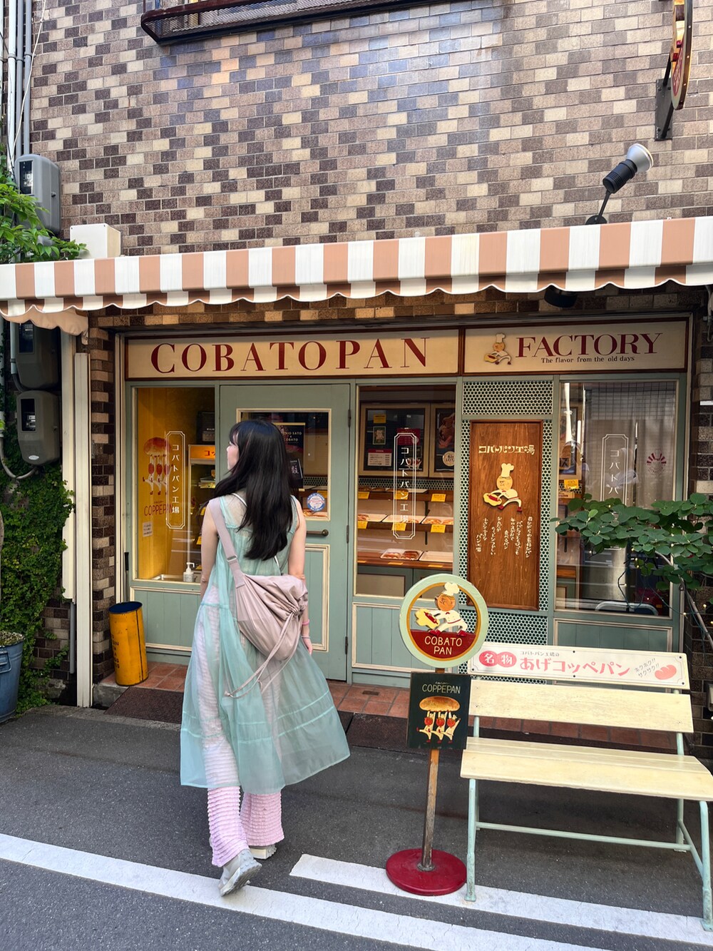 グリーン系のジャンパースカート、ピンク系のスラックス、ピンク系のショルダーバッグを着用したレディースの夏コーディネートの2枚目の写真