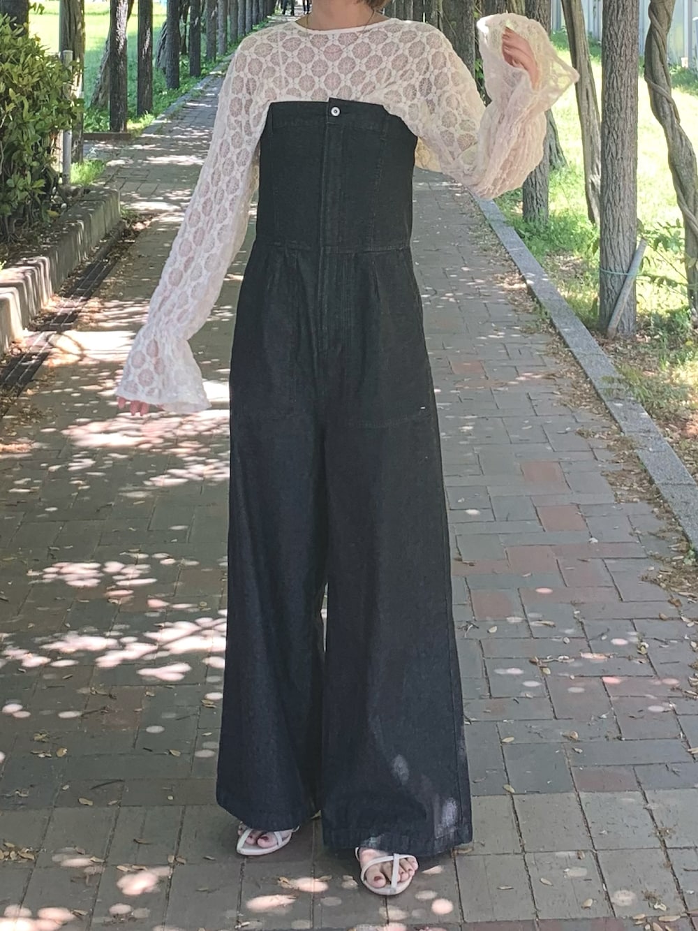 ホワイト系のTシャツ/カットソー、ブラック系のサロペット/オーバーオール、ホワイト系のサンダルを着用したレディースの春コーディネートの2枚目の写真