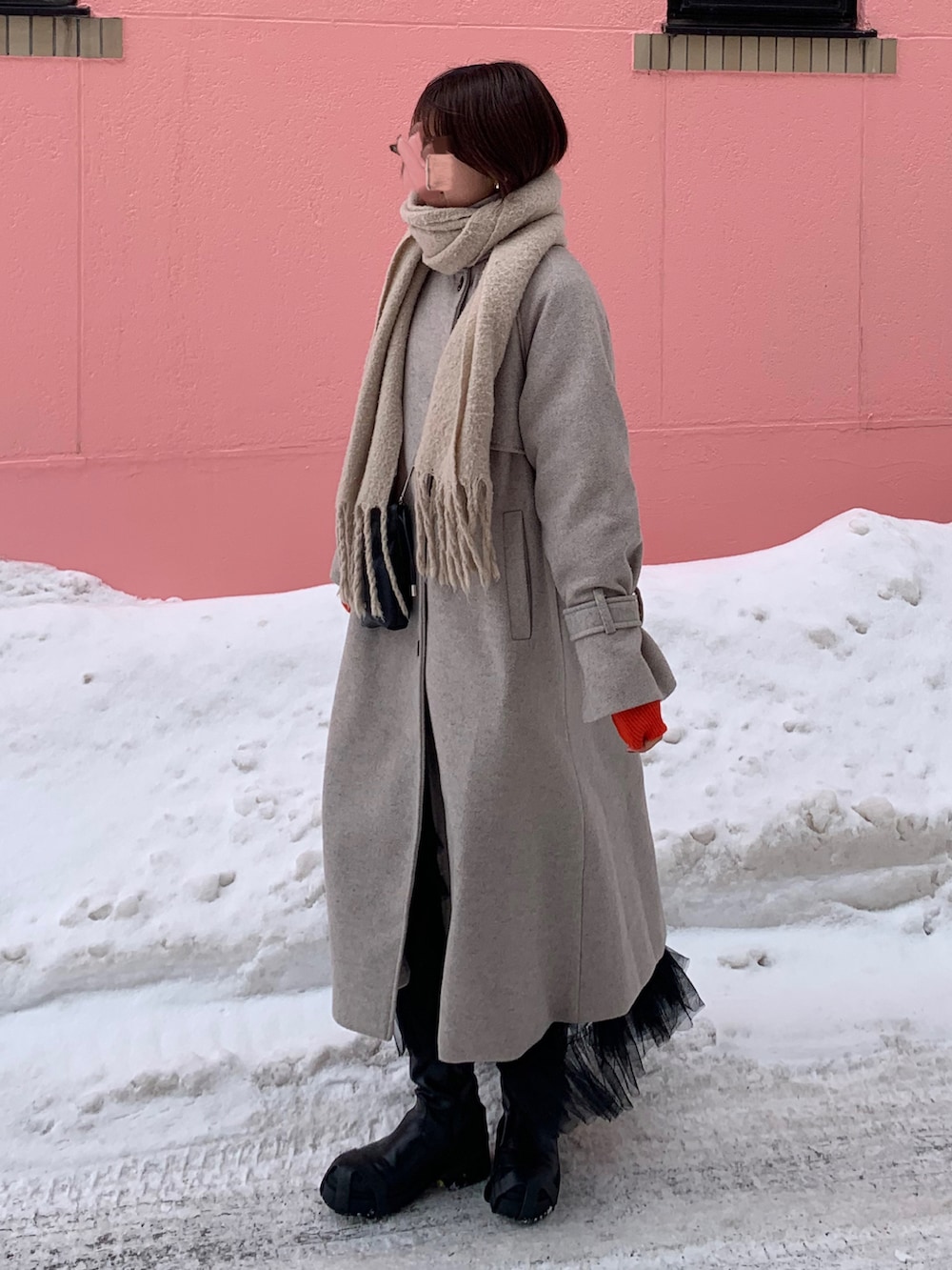 ブラウン系のトレンチコート、オレンジ系のニット/セーター、ブラック系のショルダーバッグを着用したレディースの冬コーディネートの2枚目の写真