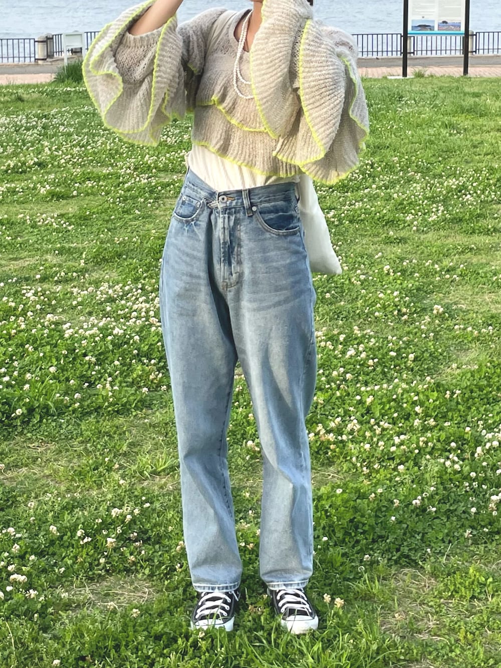 グレー系のニット/セーター、ブルー系のデニムパンツ、ブラック系のスニーカーを着用したレディースの春コーディネートの3枚目の写真