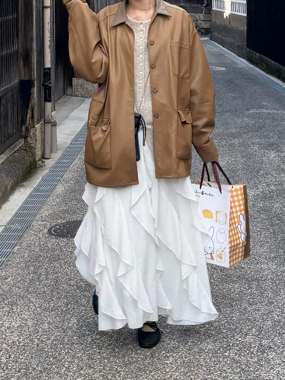 ブラック系のバレエシューズ、ベージュ系のカーディガン/ボレロ、ホワイト系のスカートを着用したレディースの春コーディネートの2枚目の写真