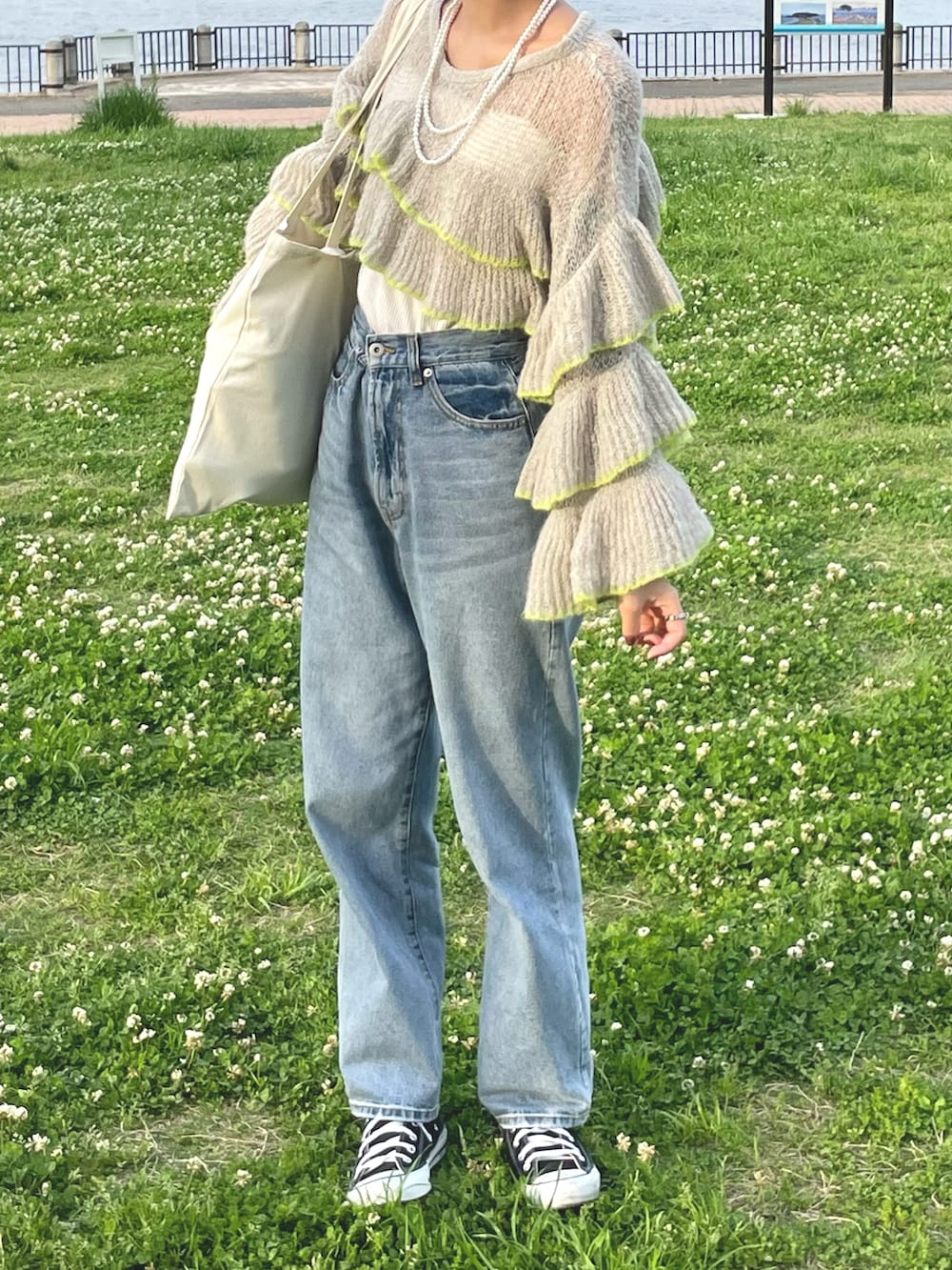 グレー系のニット/セーター、ブルー系のデニムパンツ、ブラック系のスニーカーを着用したレディースの春コーディネートの2枚目の写真