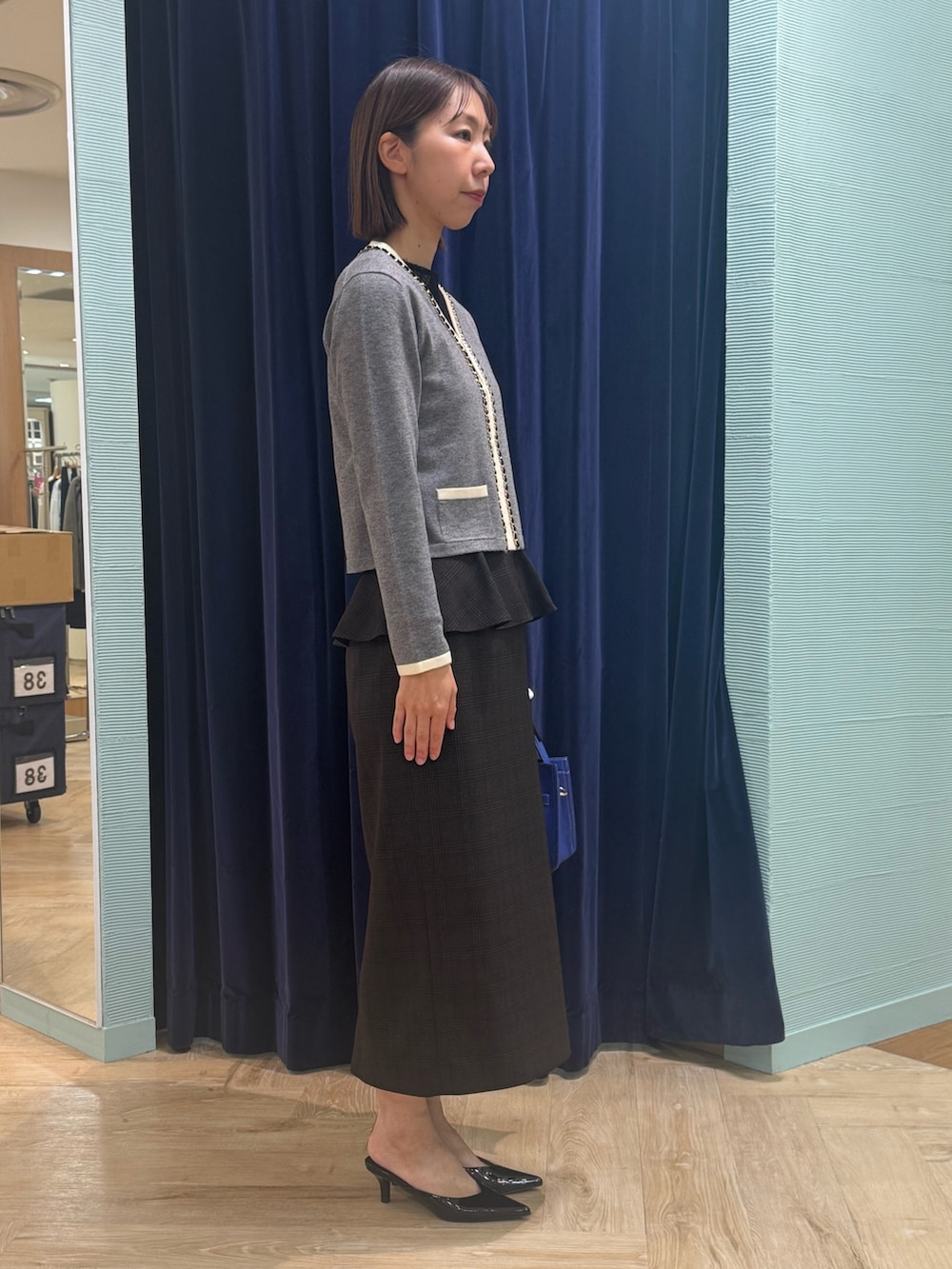 ベージュ系のスカート、グレー系のカーディガン/ボレロ、ブルー系のショルダーバッグを着用したレディースの秋コーディネートの3枚目の写真