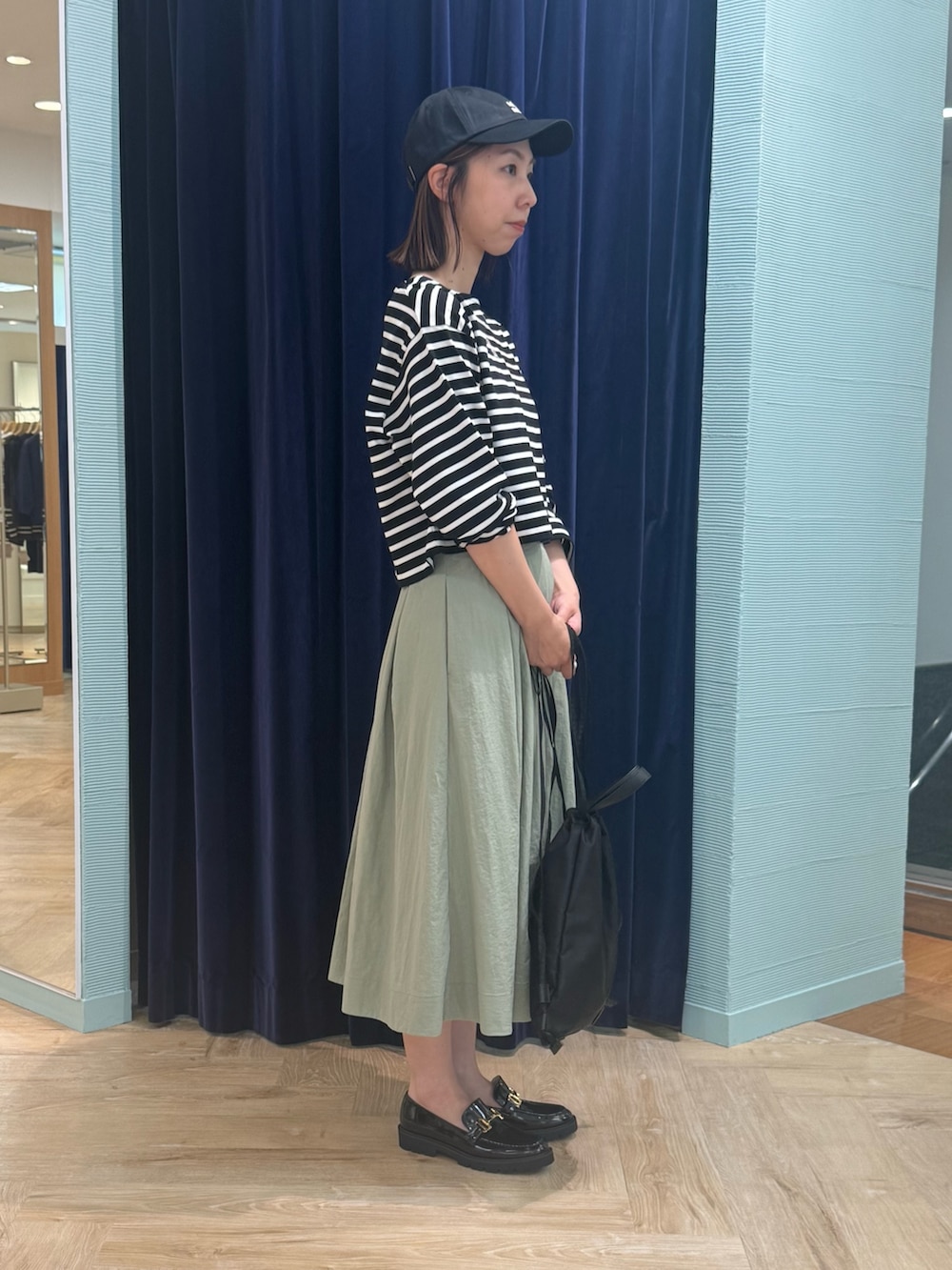 グリーン系のスカート、ブラック系のTシャツ/カットソー、ブラック系のショルダーバッグを着用したレディースの秋コーディネートの3枚目の写真