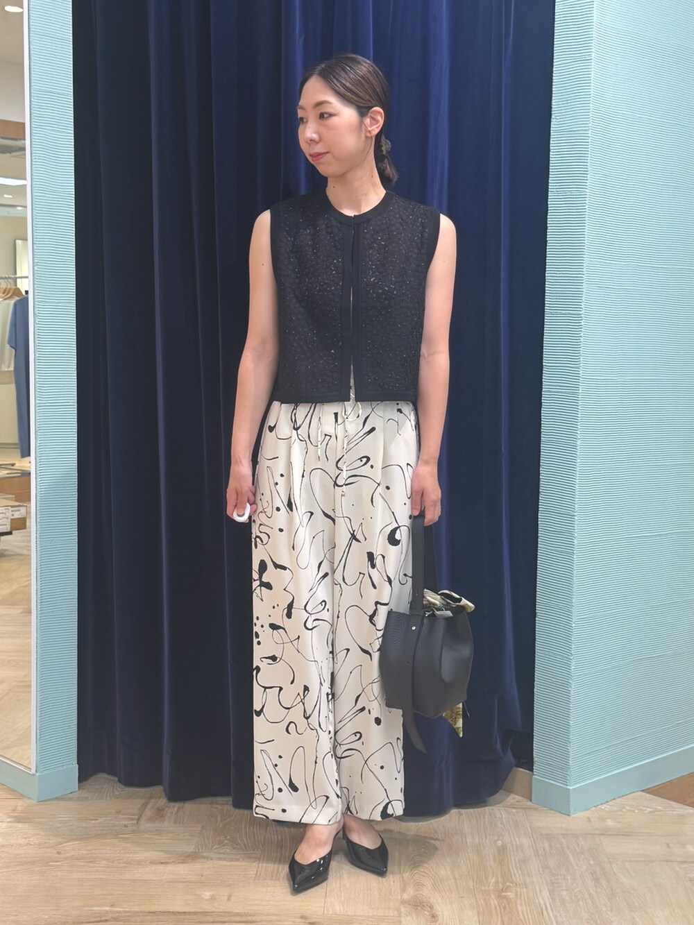 ホワイト系のその他パンツ、ブラック系のベスト、レッド系のバッグを着用したレディースの秋コーディネートの2枚目の写真