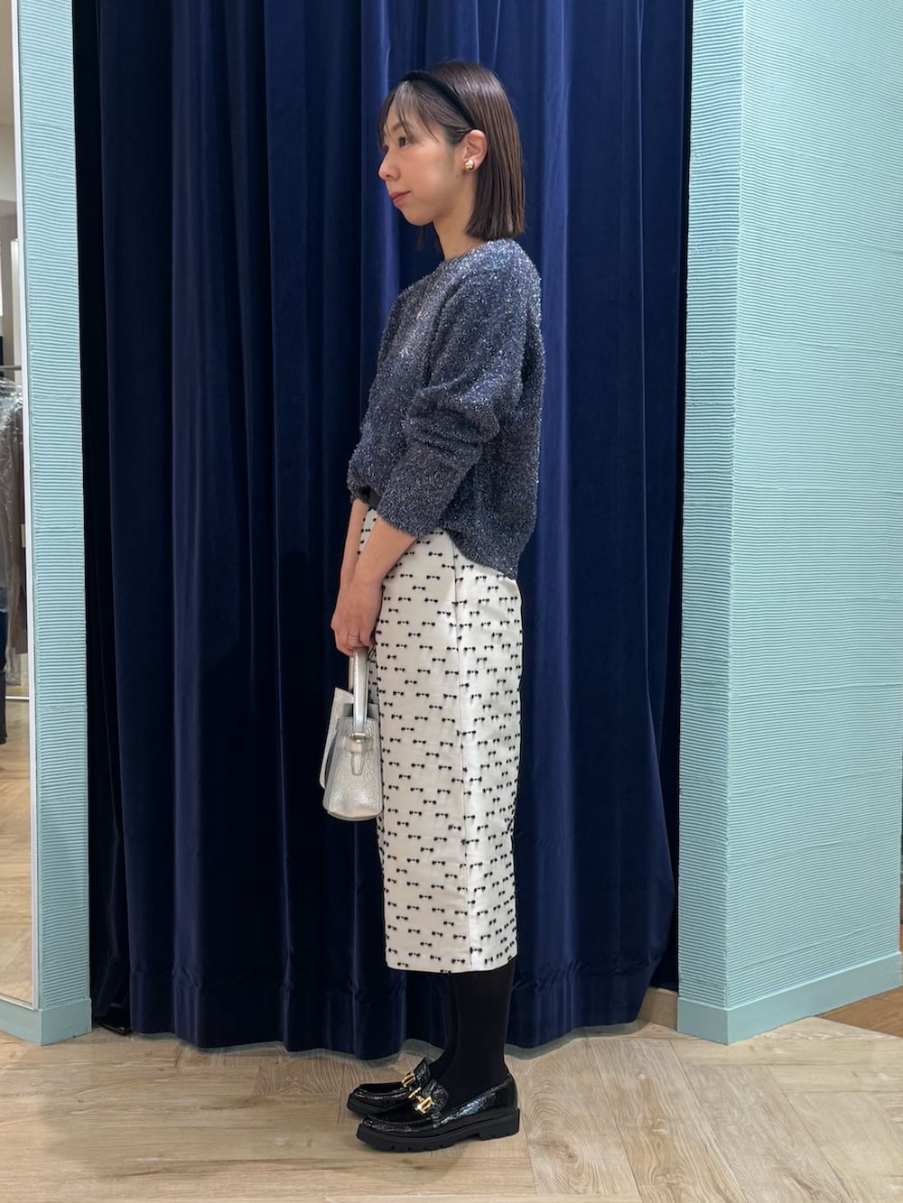 ベージュ系のスカート、ブルー系のニット/セーター、シルバー系のショルダーバッグを着用したレディースの冬コーディネートの5枚目の写真