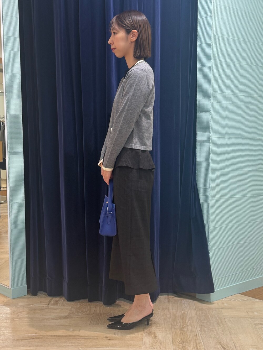 ベージュ系のスカート、グレー系のカーディガン/ボレロ、ブルー系のショルダーバッグを着用したレディースの秋コーディネートの5枚目の写真