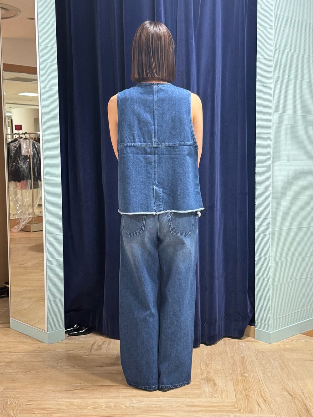 ブルー系のベスト、ブルー系のデニムパンツ、ブラウン系のショルダーバッグを着用したレディースの秋コーディネートの4枚目の写真