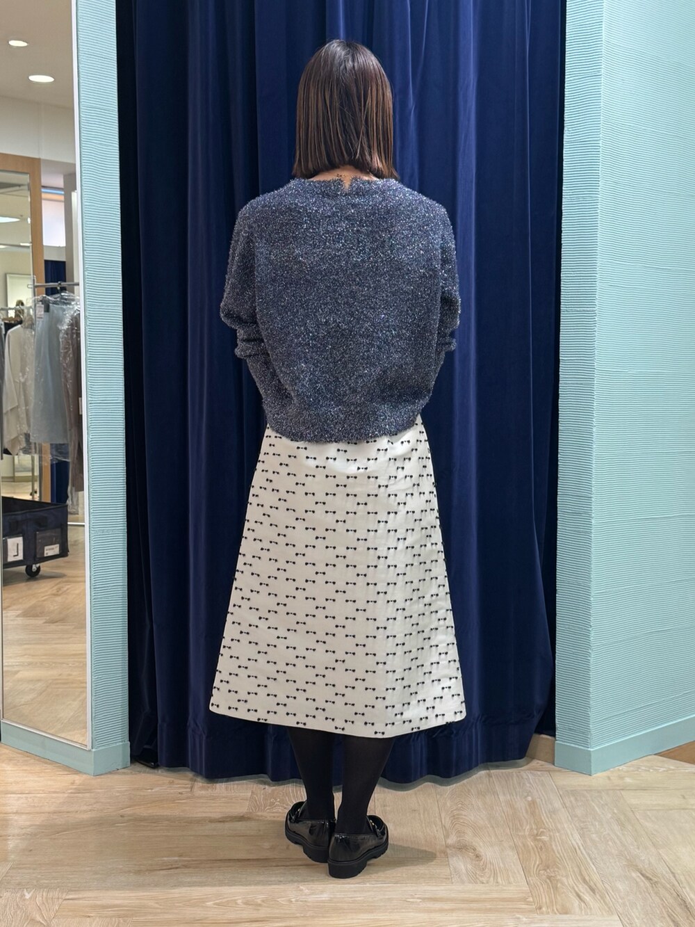 ベージュ系のスカート、ブルー系のニット/セーター、シルバー系のショルダーバッグを着用したレディースの冬コーディネートの4枚目の写真