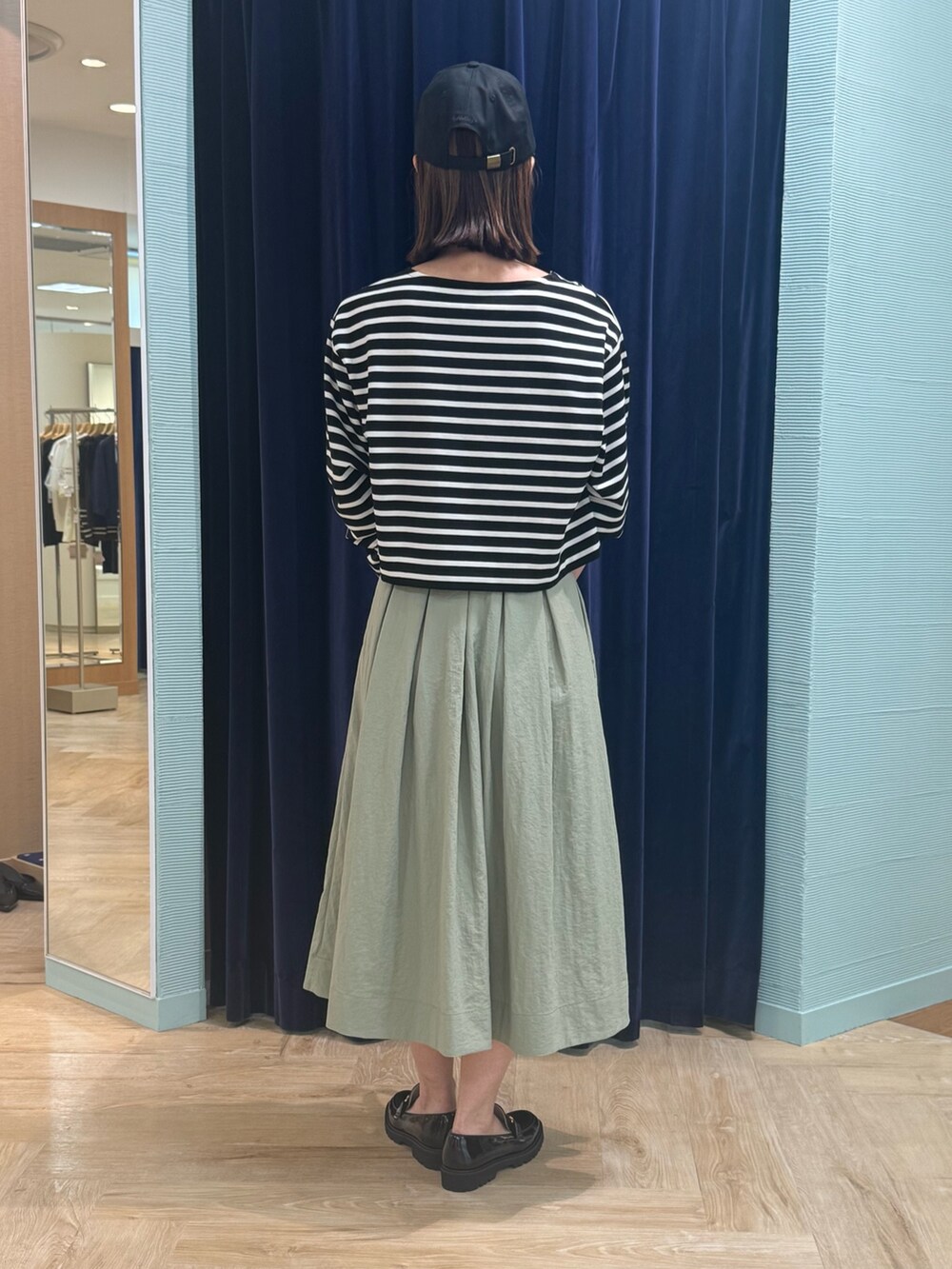 グリーン系のスカート、ブラック系のTシャツ/カットソー、ブラック系のショルダーバッグを着用したレディースの秋コーディネートの4枚目の写真