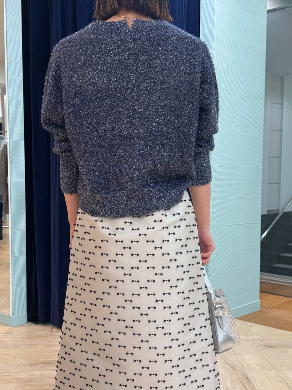 ベージュ系のスカート、ブルー系のニット/セーター、シルバー系のショルダーバッグを着用したレディースの冬コーディネートの7枚目の写真