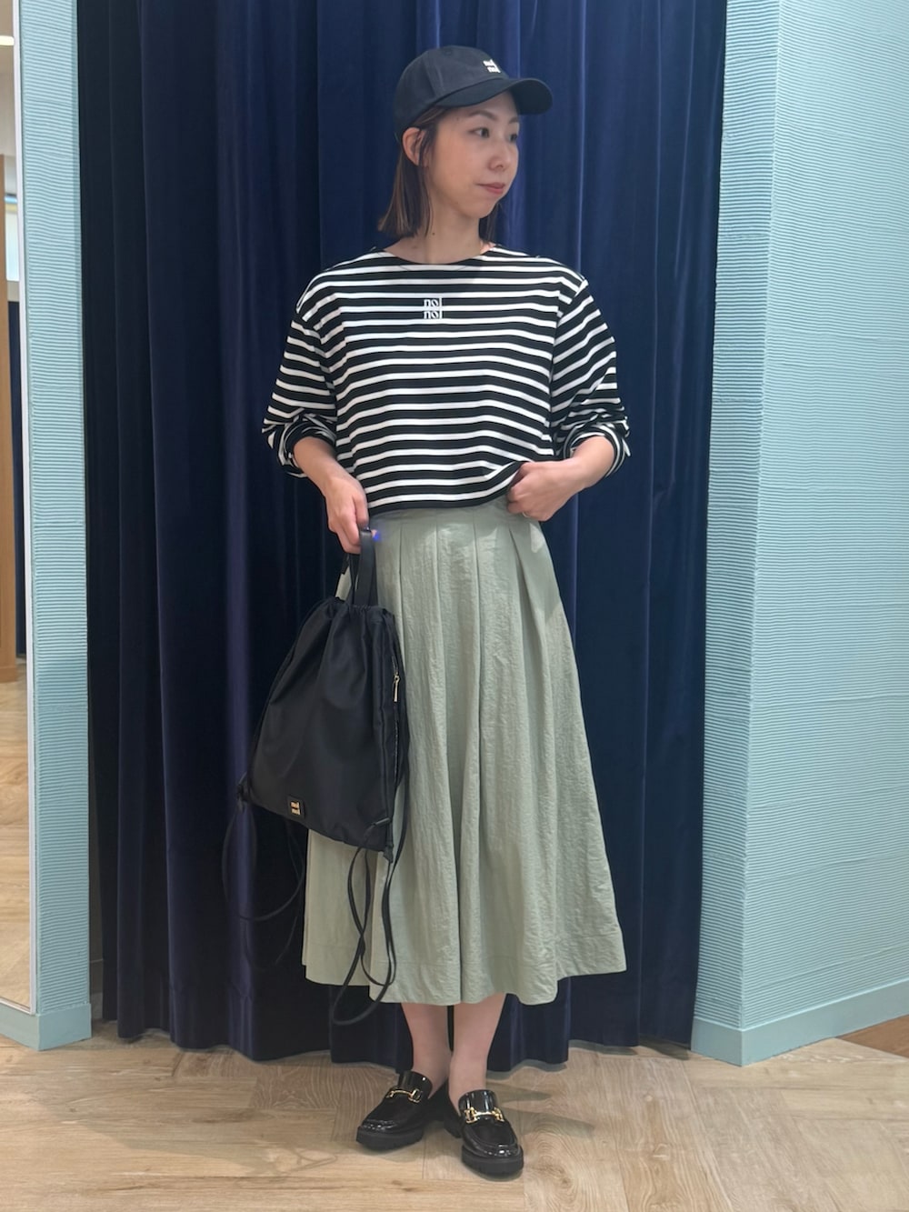 グリーン系のスカート、ブラック系のTシャツ/カットソー、ブラック系のショルダーバッグを着用したレディースの秋コーディネートの2枚目の写真