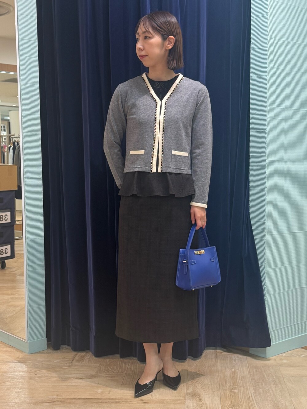 ベージュ系のスカート、グレー系のカーディガン/ボレロ、ブルー系のショルダーバッグを着用したレディースの秋コーディネートの2枚目の写真