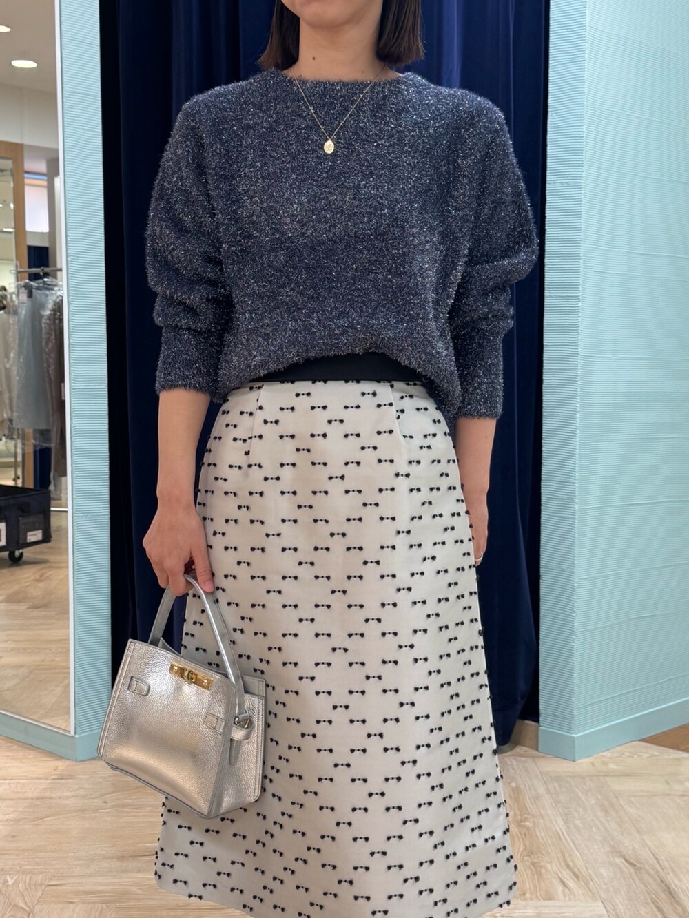 ベージュ系のスカート、ブルー系のニット/セーター、シルバー系のショルダーバッグを着用したレディースの冬コーディネートの6枚目の写真