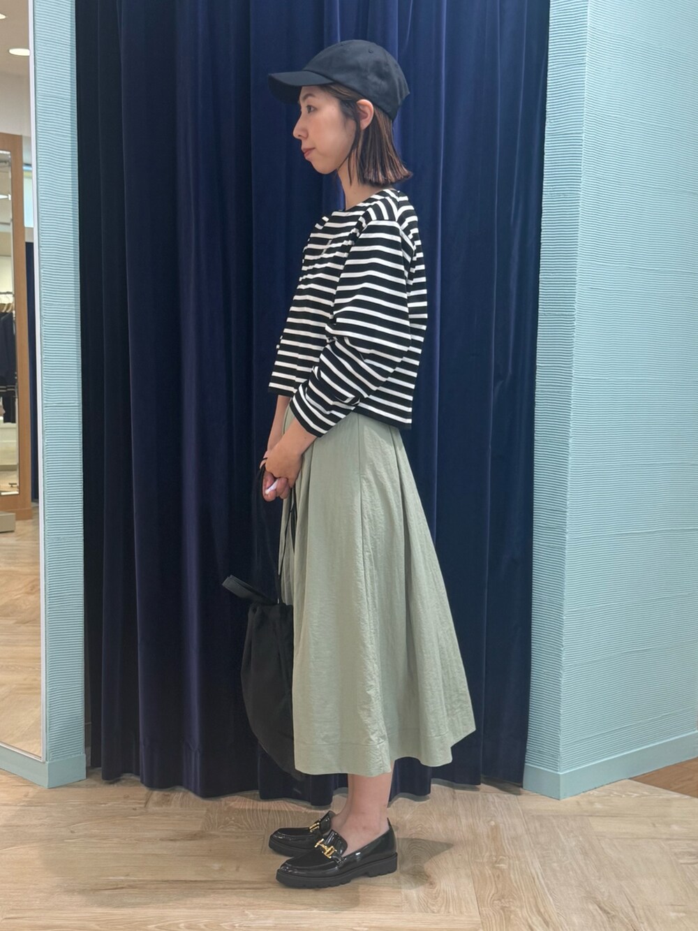 グリーン系のスカート、ブラック系のTシャツ/カットソー、ブラック系のショルダーバッグを着用したレディースの秋コーディネートの5枚目の写真