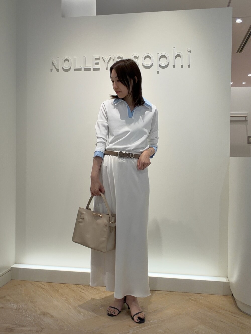 ホワイト系のニット/セーター、ホワイト系のスカート、ベージュ系のトートバッグを着用したレディースの春コーディネートの2枚目の写真