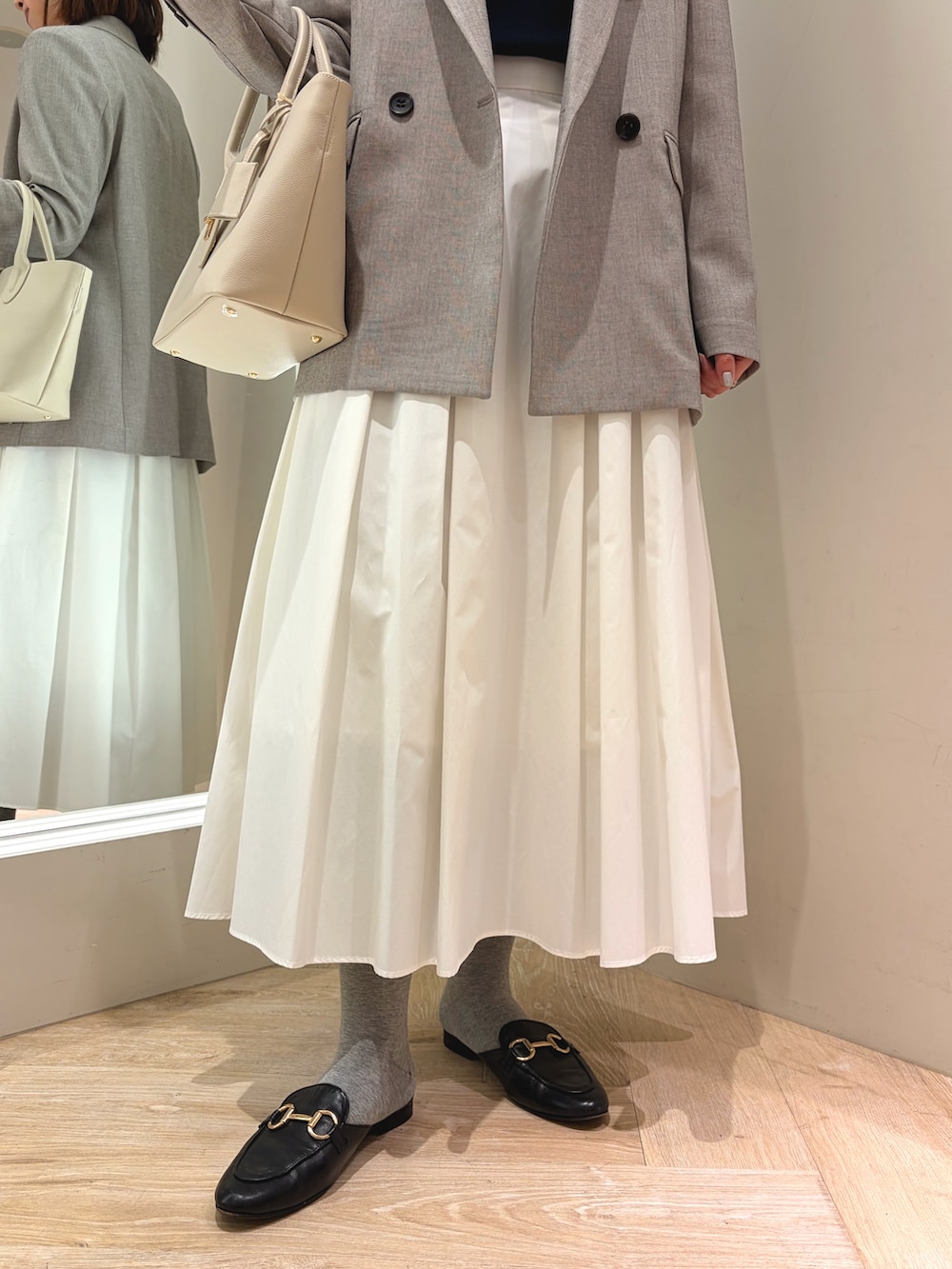 ホワイト系のスカート、ベージュ系のテーラードジャケット、ベージュ系のトートバッグを着用したレディースの春コーディネートの7枚目の写真