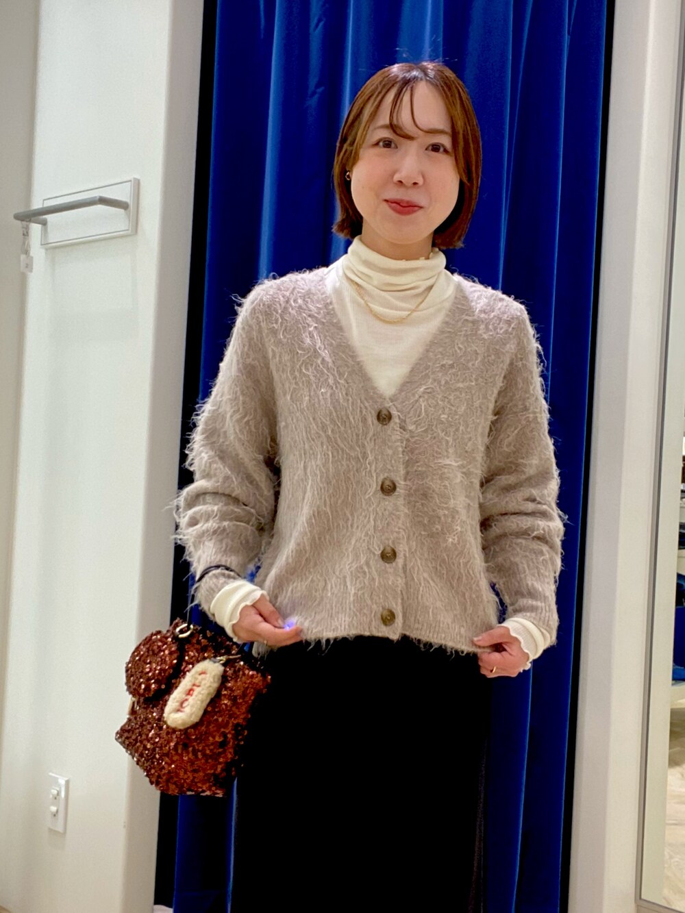 ベージュ系のカーディガン/ボレロ、ブラック系のスカート、ブラウン系のショルダーバッグを着用したレディースの冬コーディネートの5枚目の写真
