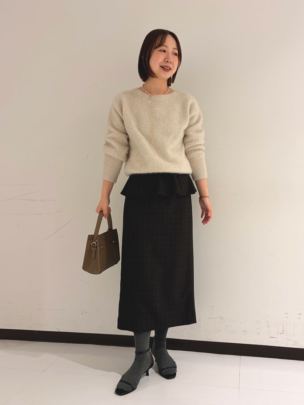ベージュ系のニット/セーター、ベージュ系のスカートを着用したレディースの秋コーディネートの4枚目の写真