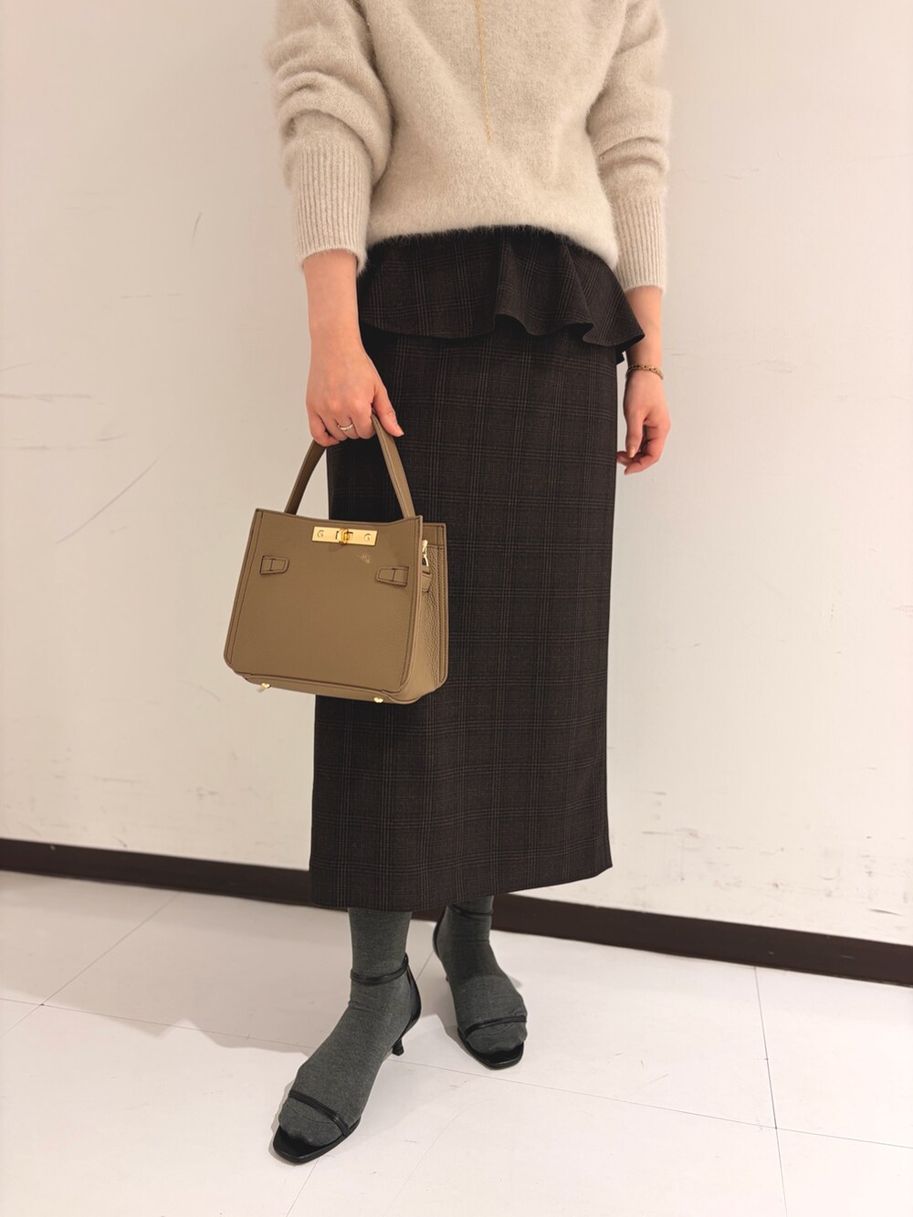 ベージュ系のニット/セーター、ベージュ系のスカートを着用したレディースの秋コーディネートの8枚目の写真