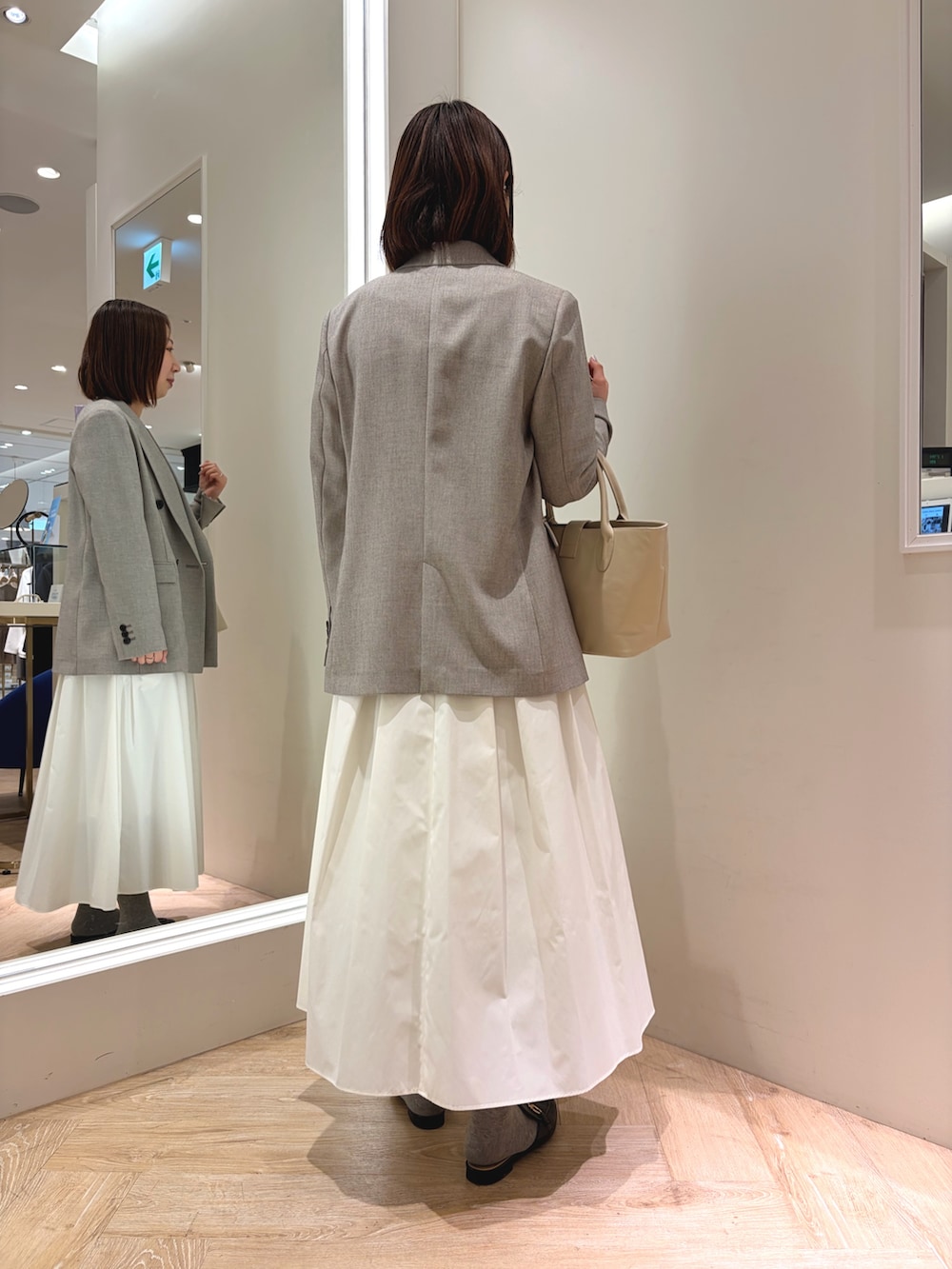 ホワイト系のスカート、ベージュ系のテーラードジャケット、ベージュ系のトートバッグを着用したレディースの春コーディネートの4枚目の写真