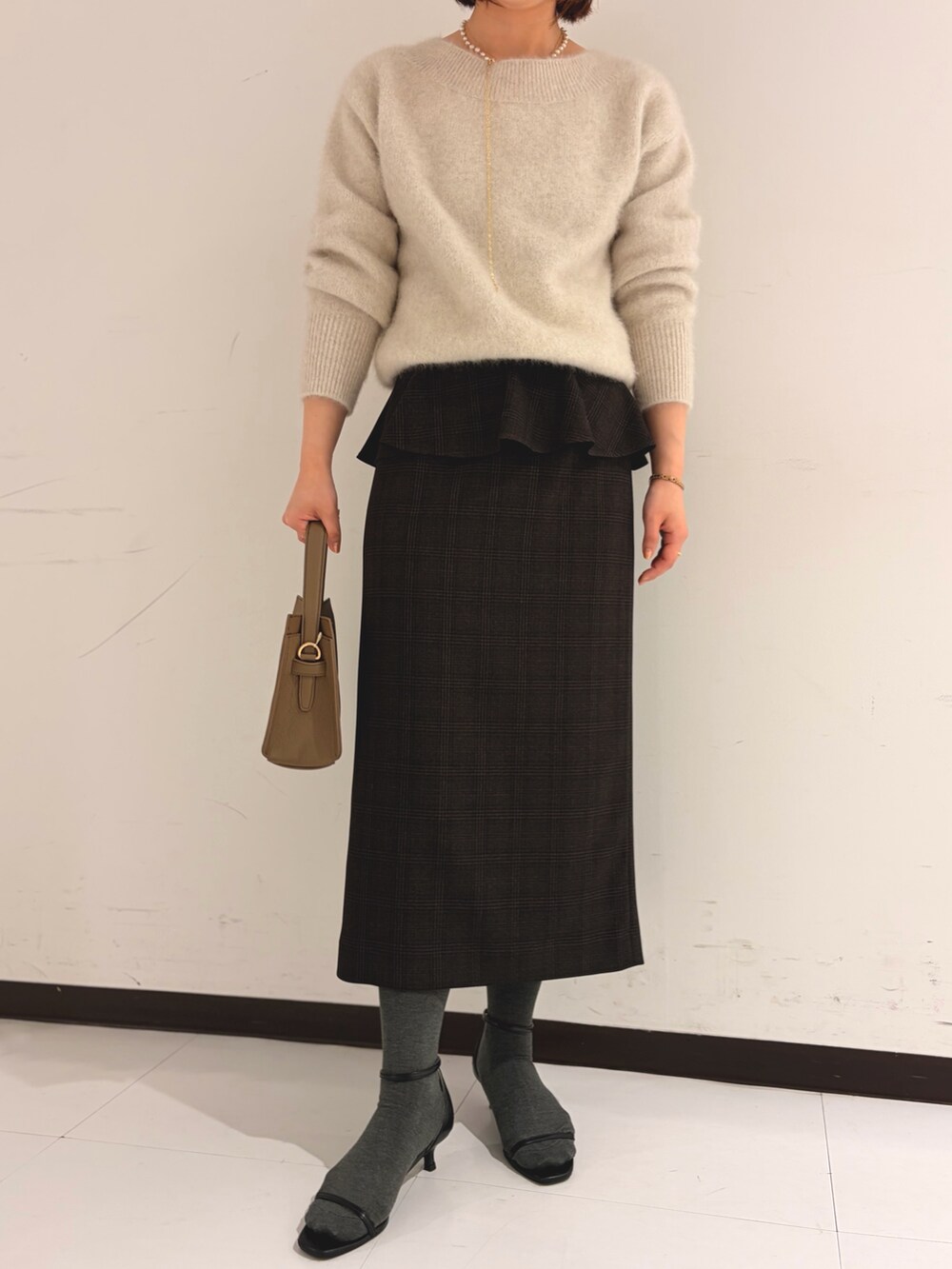 ベージュ系のニット/セーター、ベージュ系のスカートを着用したレディースの秋コーディネートの7枚目の写真