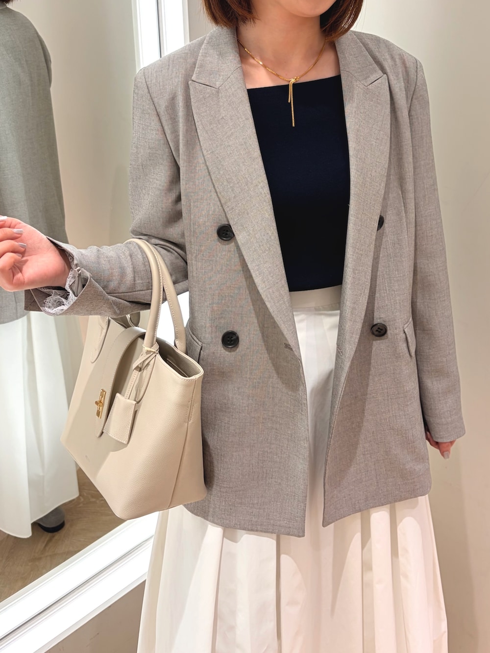 ホワイト系のスカート、ベージュ系のテーラードジャケット、ベージュ系のトートバッグを着用したレディースの春コーディネートの6枚目の写真